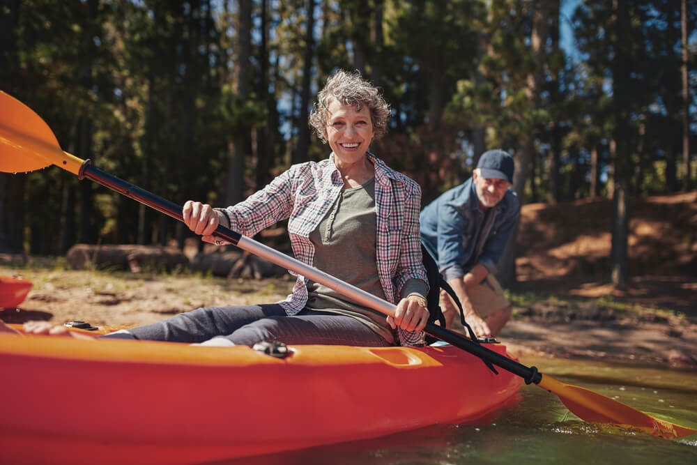 happy senior woman in a kayak holding paddles